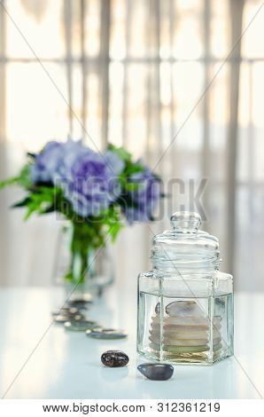 Five Donuts And Polished Stone Of Smokey Quartz Put Into A Glass Jar With Distilled Water Are On The