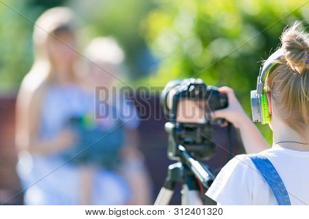 The Child Makes His First Videos On The Street In The City Park. Girl Novice Videoblogger Shoots At 