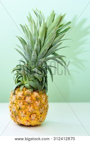 Pineapple On White Wooden Table Over Neo Mint Background. Tropical Summer Vacation And Beach Party.