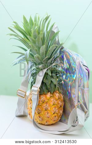Pineapple With Holographic Bag On White Wooden Table Over Neo Mint Background. Tropical Summer Vacat