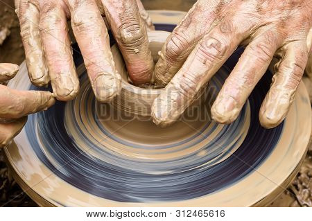 Potter’s Fingers Touch The Shapeless Piece Of Clay On The Rotating Wheel