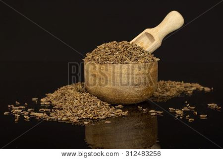 Lot Of Whole Dry Caraway Fruits In A Wooden Bowl With Wooden Scoop Isolated On Black Glass