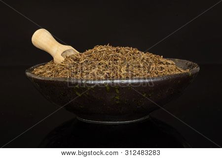 Lot Of Whole Dry Caraway Fruits In A Ceramic Bowl With Wooden Scoop In It Isolated On Black Glass