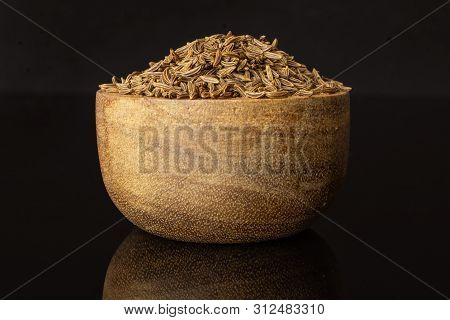 Lot Of Whole Dry Caraway Fruits Closeup In A Wooden Bowl Isolated On Black Glass