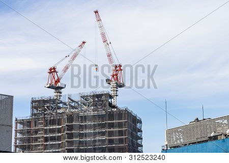 Construction Crane On Top Of Tower Working To Build High Skycrapper Office Building In The Developme