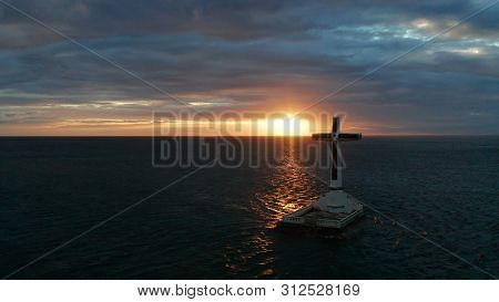 Catholic Cross In Sunken Cemetery In The Sea At Sunset, Aerial Drone. Colorful Sky During The Sunset