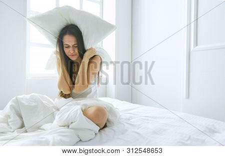 Young Caucasian Woman Covering Her Head And Ears With Pillows.