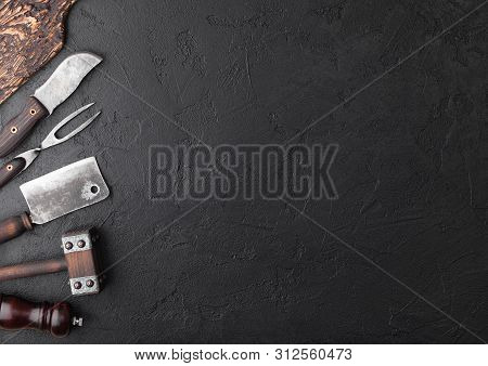 Vintage Meat Knife And Fork And Hatchets With Vintage Chopping Board And Black Table Background. But