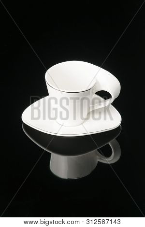 Porcelain Clay Cup For Coffee Or Tea With Sauser On The Black Mirror Background. Copy Space.