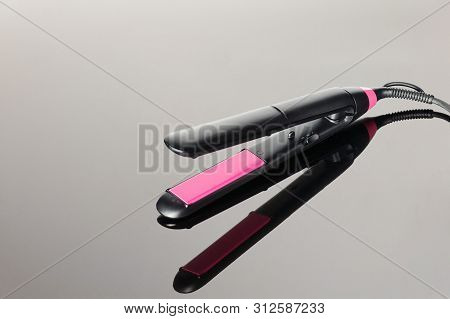 Electrical Hair Iron For Household On The Grey Mirror Background With Copy Space
