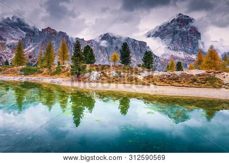 Picturesque Autumn Landscape, Alpine Glacier Lake And Yellow Larches, Limides Lake With Snowy Tofana