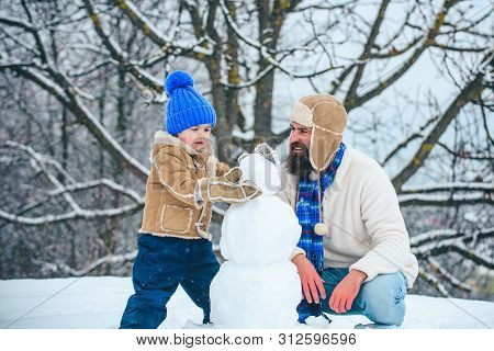 Merry Christmas And Happy New Year. Happy Father And Son Making Snowman In The Snow. Handmade Funny 