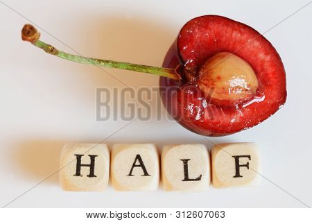 A Half Of A Red Juicy Cherry On A Light Background Next To The Letters. Macro And Education. Dayligh