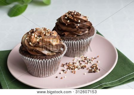 Two Chocolate Cupcakes With Delicate Hats, Placed On A Pink Plate