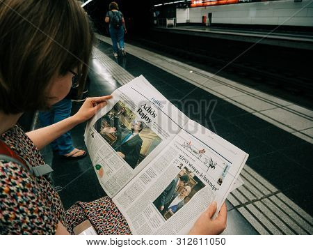 Barcelona - June 1 2018: Curious Young Woman Reading In Barcelona Metro Station The La Vanguardia Ne