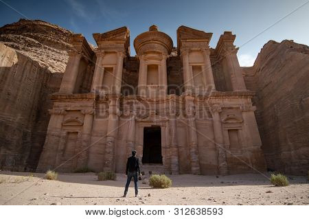 Young Asian Man Traveler And Photographer Holding Camera Standing At Ad Deir Or El Deir, The Monumen