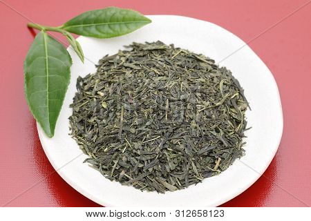 Dried Tea Leaves With Green Tea Leaves On Red Background