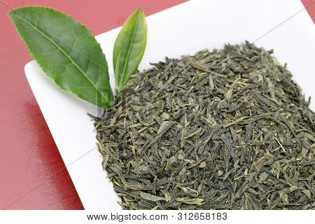 Dried Tea Leaves With Green Tea Leaves On Red Background