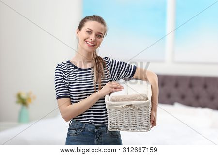 Woman Holding Wicker Basket With Folded Clean Towels In Bedroom. Laundry Day