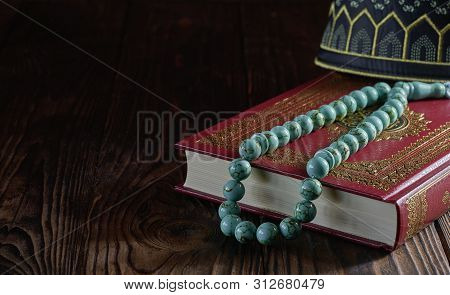 Islamic Book Koran With Rosary Beads And Kopiah Hat For Muslims On Wooden Table