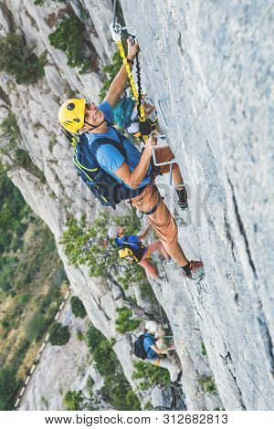 Man In Helmet And Special Equipment Climbing Mountain Via Ferrata By Sunny Day In Crimea.