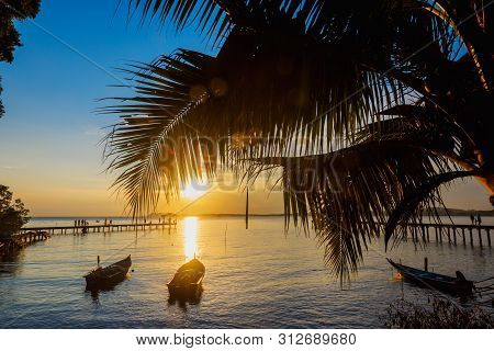 Beachside Sunset With Beautiful Boat, Bridge Coconut Trees And Cloudy Sky