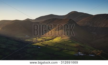 Stunning Landscape Image Of Sun Beams Lighting Up Small Area Of Mountain Side In Lake District Whils