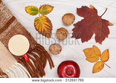 Checkered Plaid, Dry Yellow And Brown Leaves, Cup Of Coffee, Apple And Walnuts On Wooden Background.