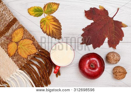 Checkered Plaid, Dry Yellow And Brown Leaves, Cup Of Coffee, Apple And Walnuts On Wooden Background.