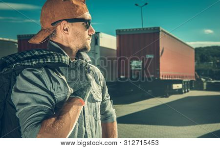 Profession Truck Driver. Caucasian Trucker In His 30s On A Truck Stop.