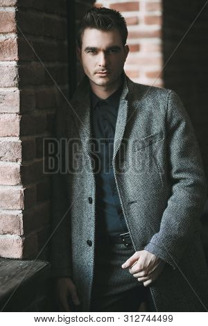 A portrait of a thoughtful fashionable young man near the wall. Casual fashion for men.