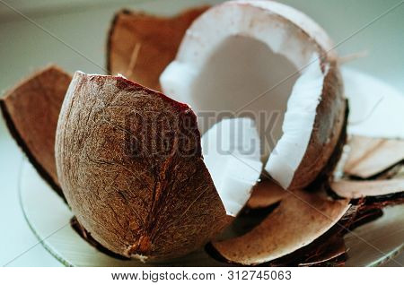 Cracked Fresh Coconut On White Table Background. Ripe Half Cut Coconut. Coconut Shell, Cream And Oil