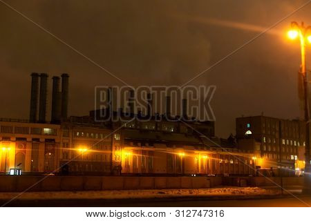 Moskow / Russia - 01.23.2017: Factory With Smoking Pipes At Night, With Yellow Lanterns.