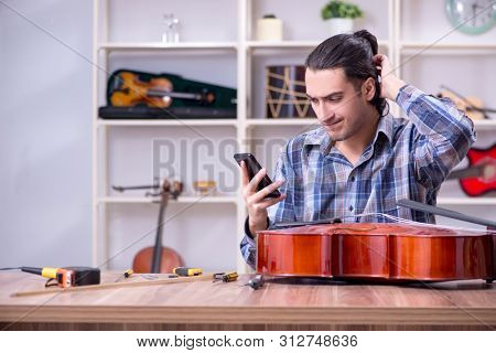 Young handsome repairman repairing cello