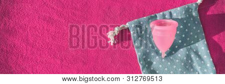 Menstrual cup feminine hygiene product for women banner reusable eco-friendly sustainable silicone bell top view on pink panoramic background of towel texture.