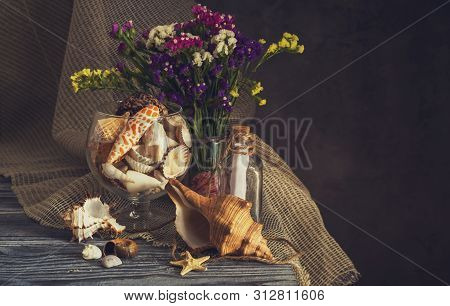 Still Life. A Variety Of Seashells, Wild Flowers (limonium Sinuatum) And Starfish On A Wooden Table 