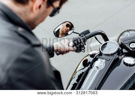 Selective Focus Of Reflection Of Young Man In Sungasses Sitting On Motorcycle