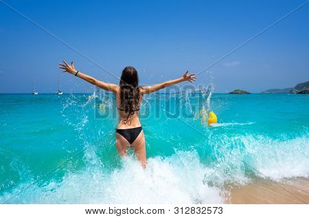 Ibiza beach girl splashing water open arms in Balearic islands