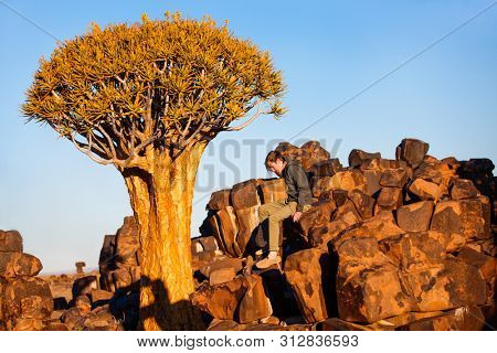 Teenage boy at quiver tree forest near Keetmanshoop in Namibia at sunset