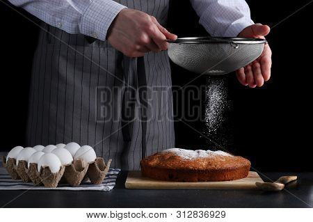 Chef Pouring Powdered Sugar On Tasty Pie On Dark Background. Ched Processing Pie Or Cake