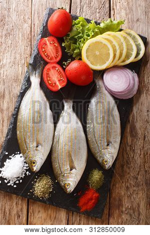 Raw Sarpa Salpa With Ingredients Close-up On A Slate Board. Vertical Top View