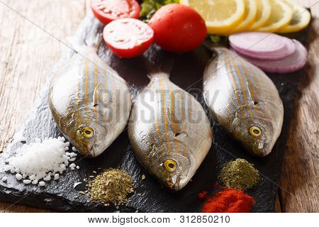 Fresh Raw Raw Sarpa Salpa Fish With Lemon, Vegetables And Spices Closeup On A Slate Board. Horizonta