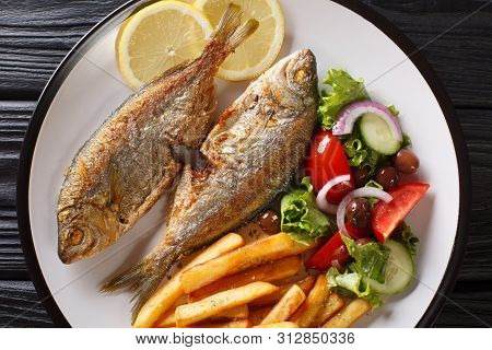 Fried Salema Porgy Fish With A Side Dish Of Fresh Salad And French Fries Close-up On A Plate. Horizo