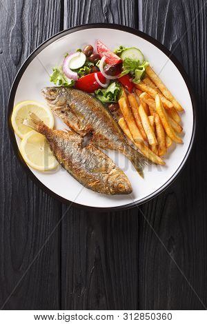 Traditional Fried Sarpa Salpa Fish With Lemon And Side Dish Of Fresh Vegetable Salad. French Fries C