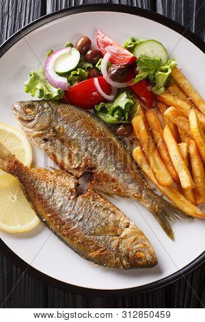 Fried Salema Porgy Fish With A Side Dish Of Fresh Salad And French Fries Close-up On A Plate. Vertic