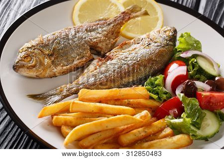 Fried Salema Porgy Fish With Lemon And Side Dish Of Fresh Vegetable Salad Close-up On A Plate. Horiz