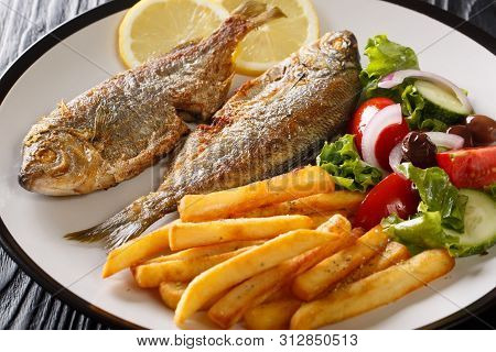 Portion Of Fried Salema Porgy Fish With Lemon And Fresh Vegetable Salad Close-up On A Plate. Horizon