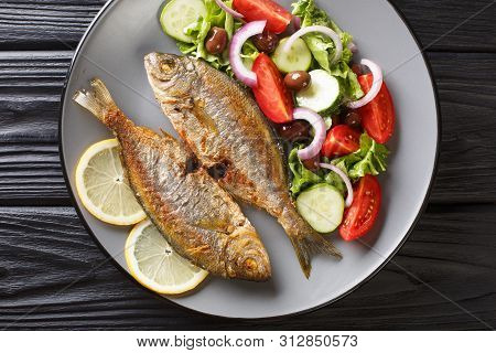 Fried Salema Porgy Sea Fish With Fresh Vegetable Salad Close-up On A Plate On The Table. Horizontal
