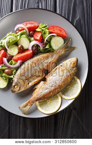 Fried Salema Porgy Sea Fish With Fresh Vegetable Salad Close-up On A Plate On The Table. Vertical To