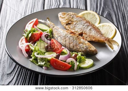 Portion Of Fried Salema Porgy Fish With Lemon And Fresh Vegetable Salad Close-up On A Plate. Horizon